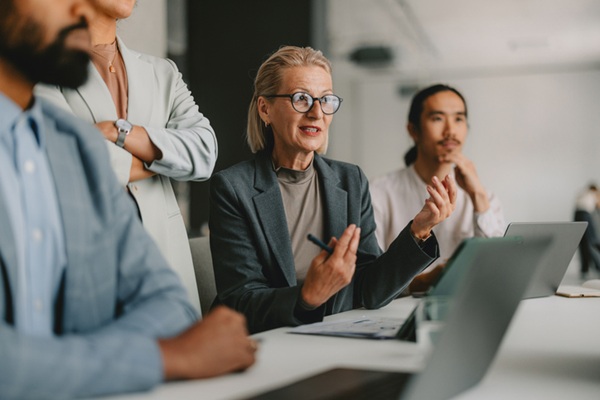 A diverse group of professional individuals engaged in a business meeting within a bright office, illustrating teamwork, collaboration, and leadership.