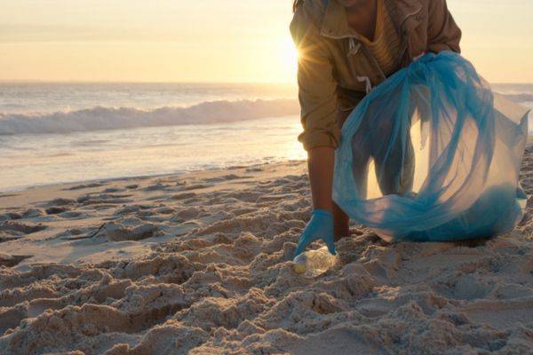 Beach cleaning, bottle and person volunteering for earth day