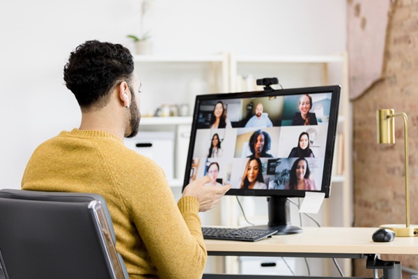 Man attends virtual staff meeting from home office
