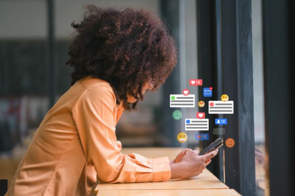 Smiling businesswoman engaging with social media on smartphone at modern workspace