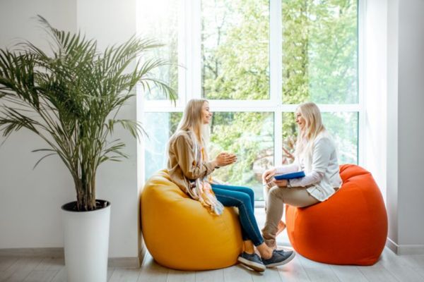 Two women sitting on bean bags and speaking to each other.