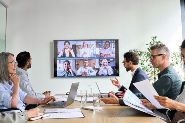 Group of colleagues in a meeting with virtual attendees.
