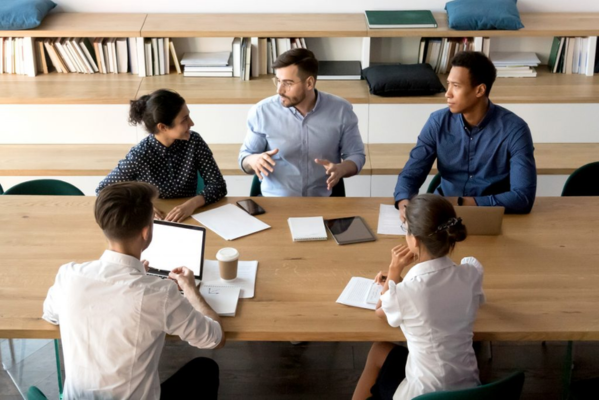 Five people in a meeting, listening to one person speaking.