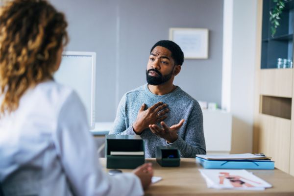 Man Expresses Concerns During Consultation With a Doctor in Modern Office Setting