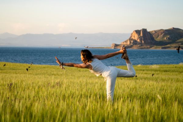 Woman practicing yoga in a field outdoors.