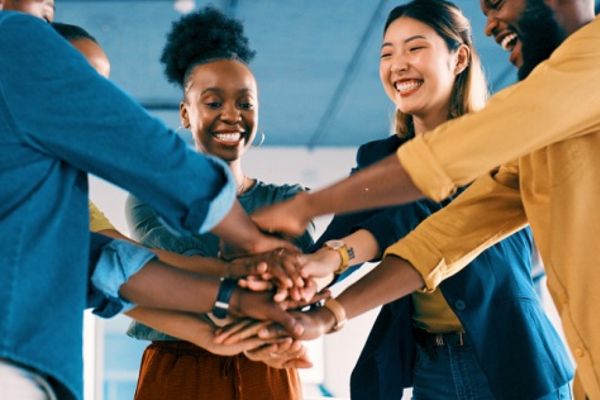 Diverse group of coworkers putting their hands together, teamwork.