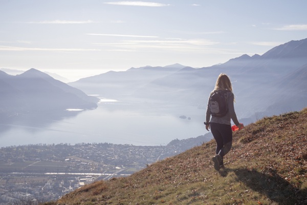 Young woman hikes along sunny mountain ridge in the morning