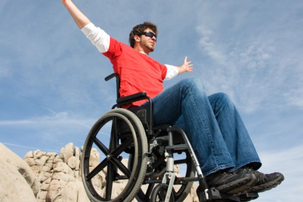 Man in a wheelchair spreading arms wide in celebration.