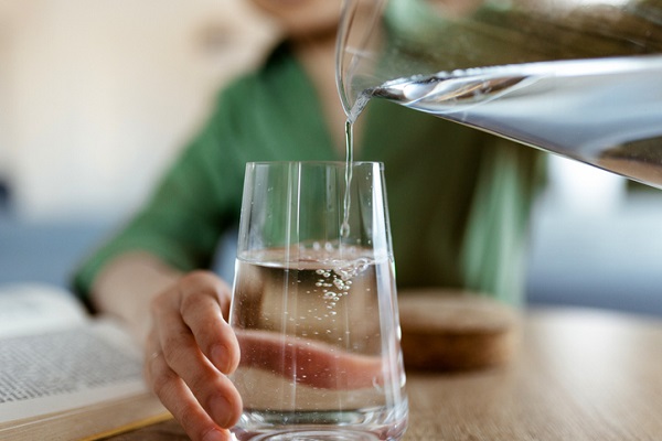 Woman Pouring Water From Jug Into Glass