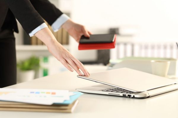 Woman closing her laptop, ending work day.