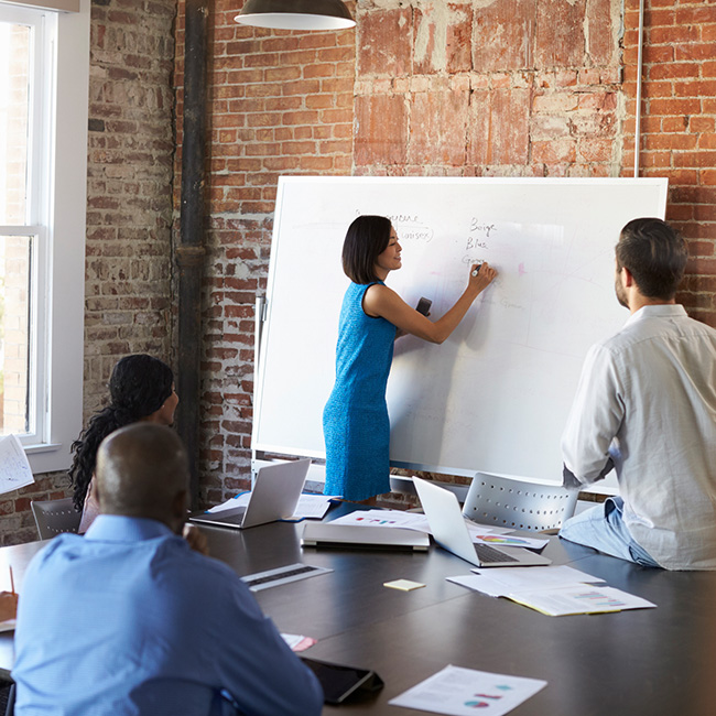 Woman at whiteboard in front of other people