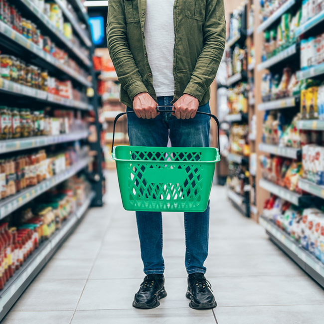 Person holding an empty basket in a store aisle